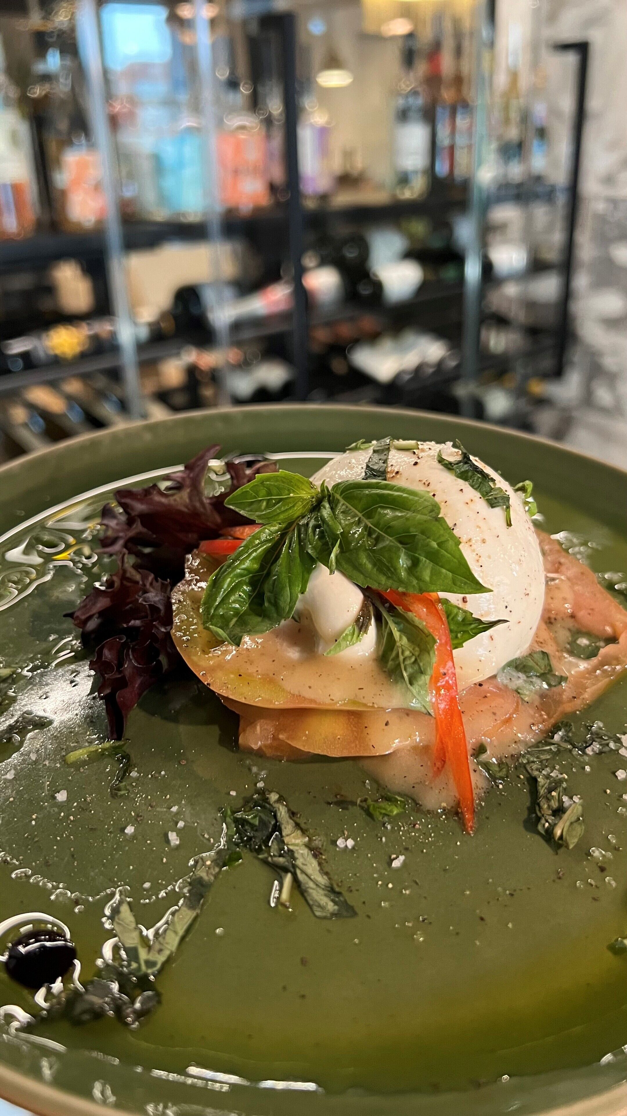 A dish with a poached egg, basil, and vegetables on a green plate.