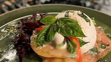 A dish with a poached egg, basil, and vegetables on a green plate.