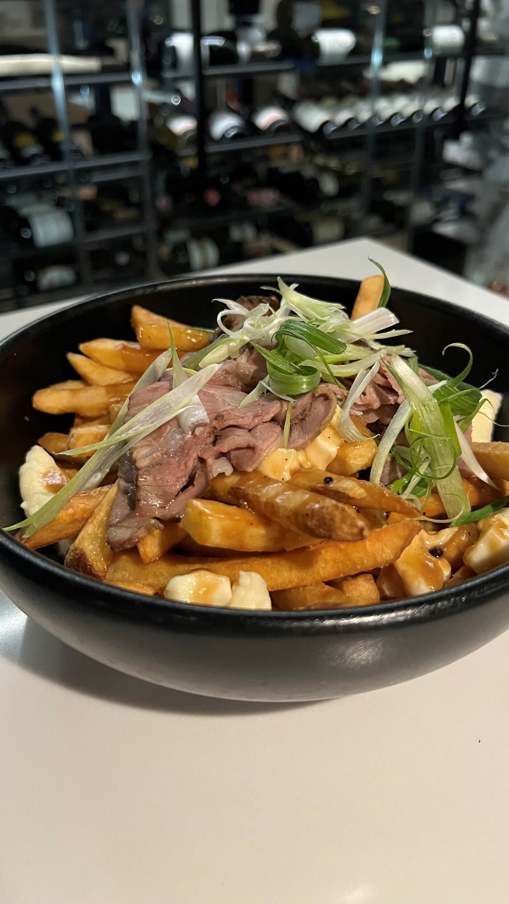 Un plat composé de frites, de viande et d’oignons verts.