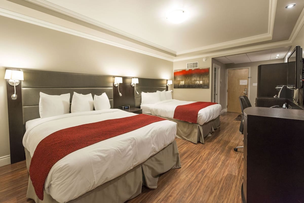 Une chambre d’hôtel avec deux lits, un bureau et une télévision.