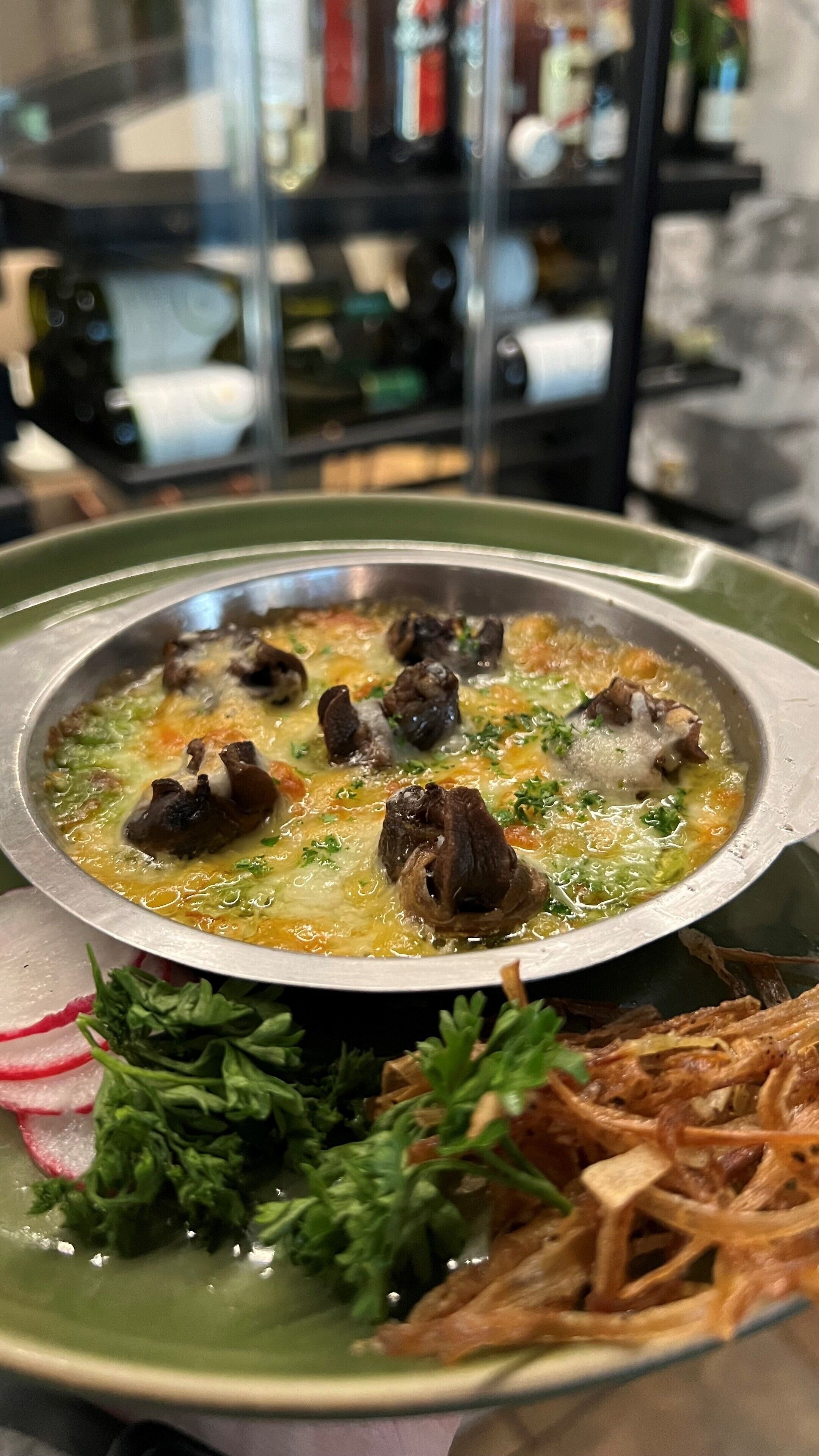 A bowl of soup with meat and vegetables, garnished with herbs, served on a plate with a green rim.