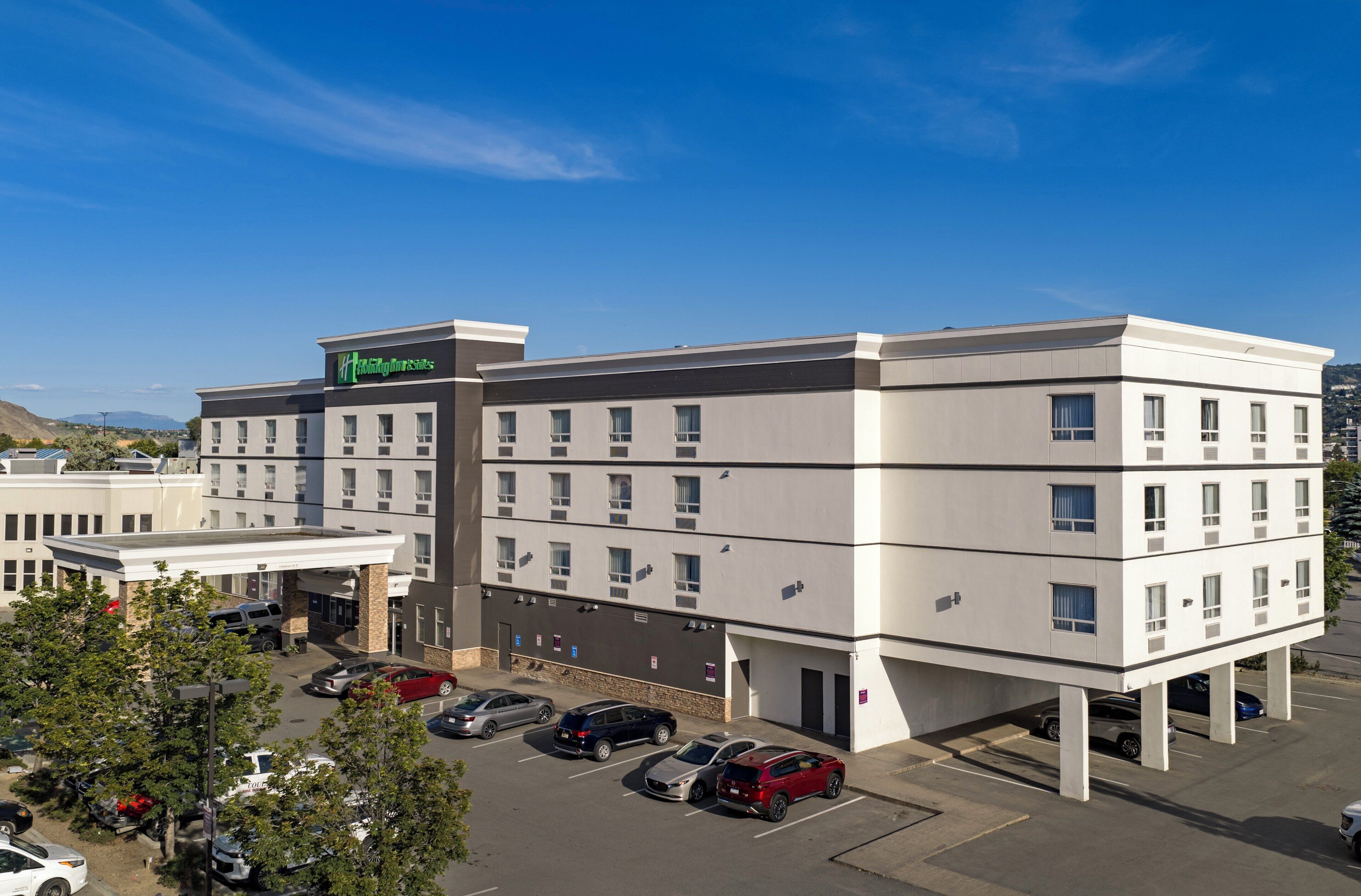 A multi-story hotel with a parking lot, a gas station, and a view of the surrounding area.