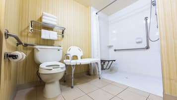 Baño con inodoro, ducha y barra de apoyo.
