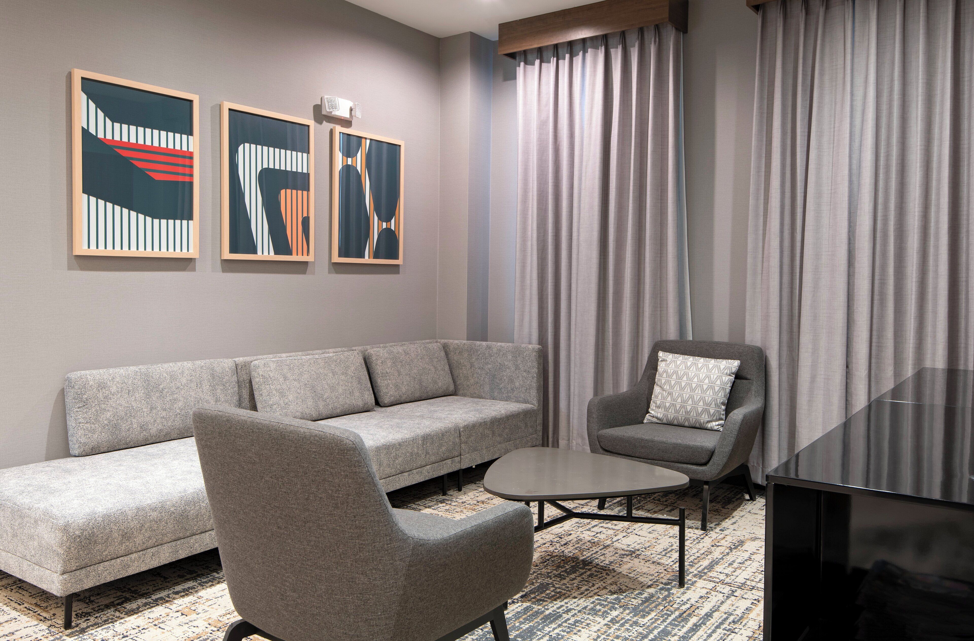 A modern living room with a grey sofa, a grey armchair, a small coffee table, and abstract art on the wall.