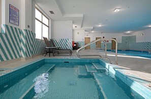 Enjoy a refreshing swim in our indoor pool, featuring a clear water surface and metal ladders for easy access.