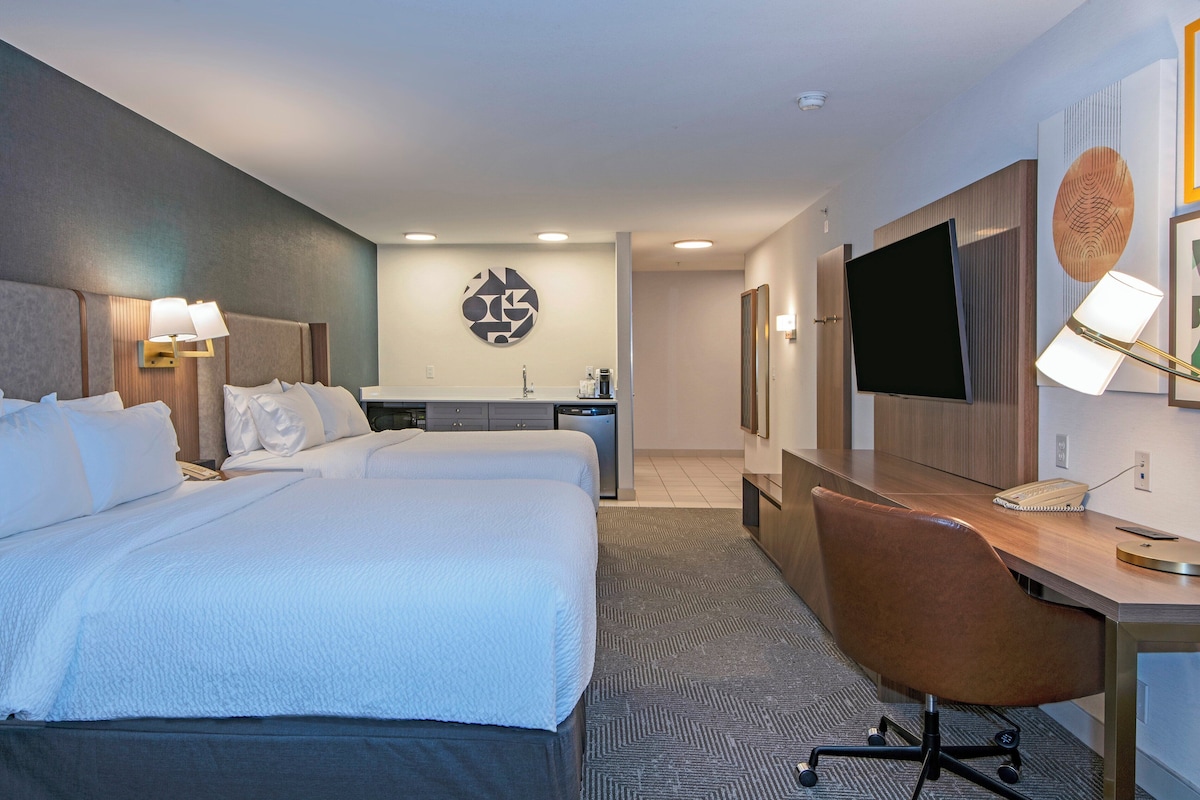 A hotel room with a large bed, a desk, and a television.