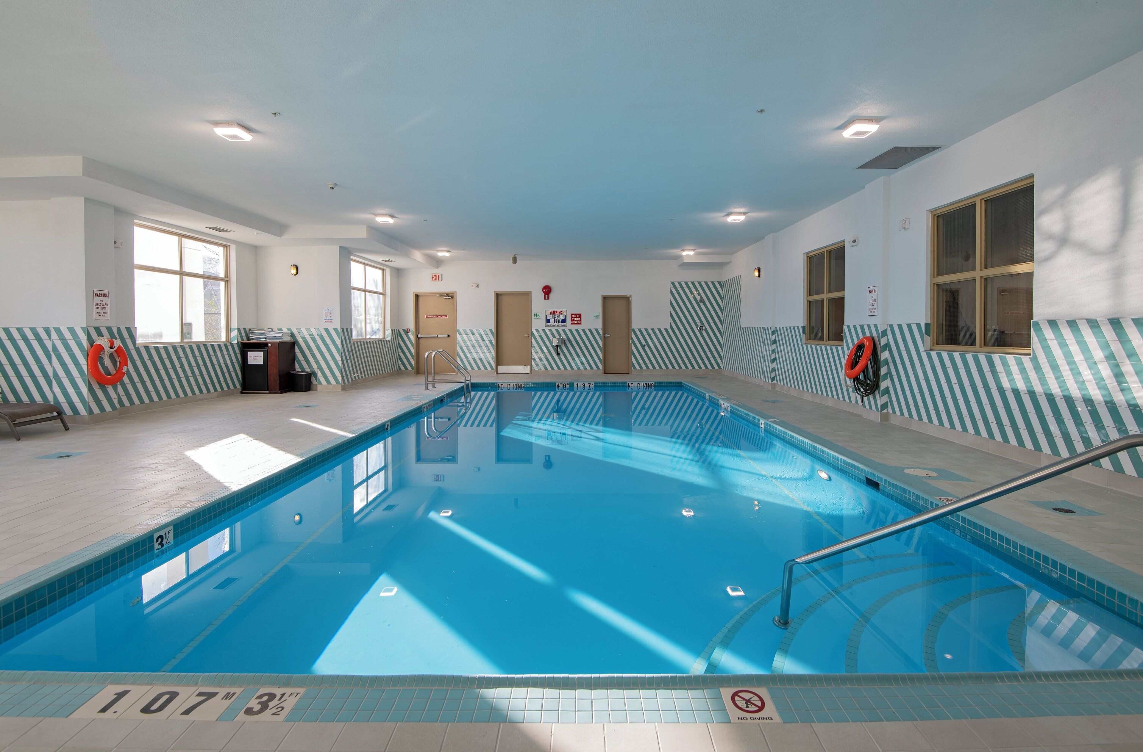 An indoor swimming pool with clear lane markings, safety signs, and a lifeguard chair.