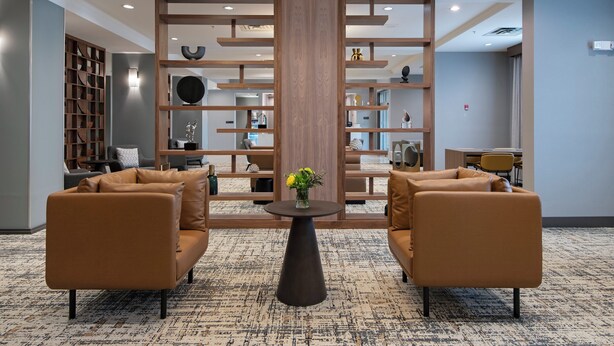 A lobby with two sofas, a central table with a vase, and a wooden partition with shelves.