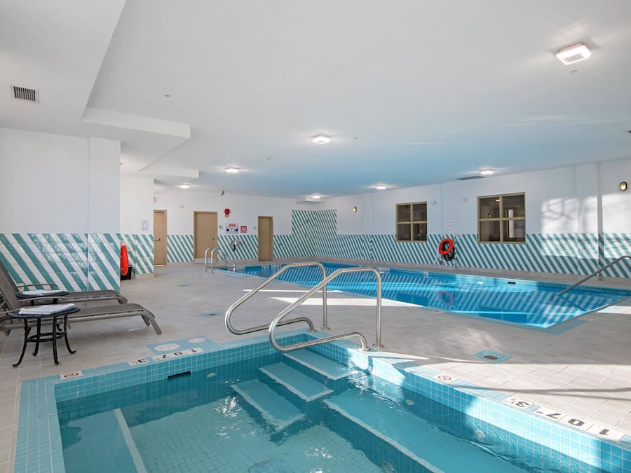 Una piscina interior con paredes de azulejos, una silla de salvavidas y una escalera de piscina.
