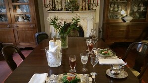 A dining table set with plates, glasses, and a vase of flowers.