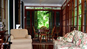 A room with a ceiling fan, a floral sofa, a patterned rug, and a dining table with chairs.