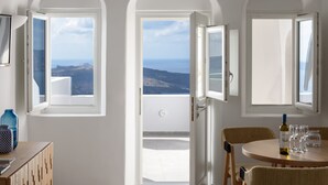 Una habitación con balcón, una mesa con copas de vino y una botella de vino.