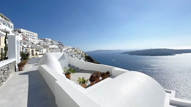Un edificio de paredes blancas con una terraza con vistas al mar.