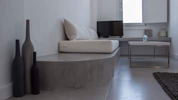 A modern living room with a curved seating area, a flat-screen TV, a small table, and two vases.
