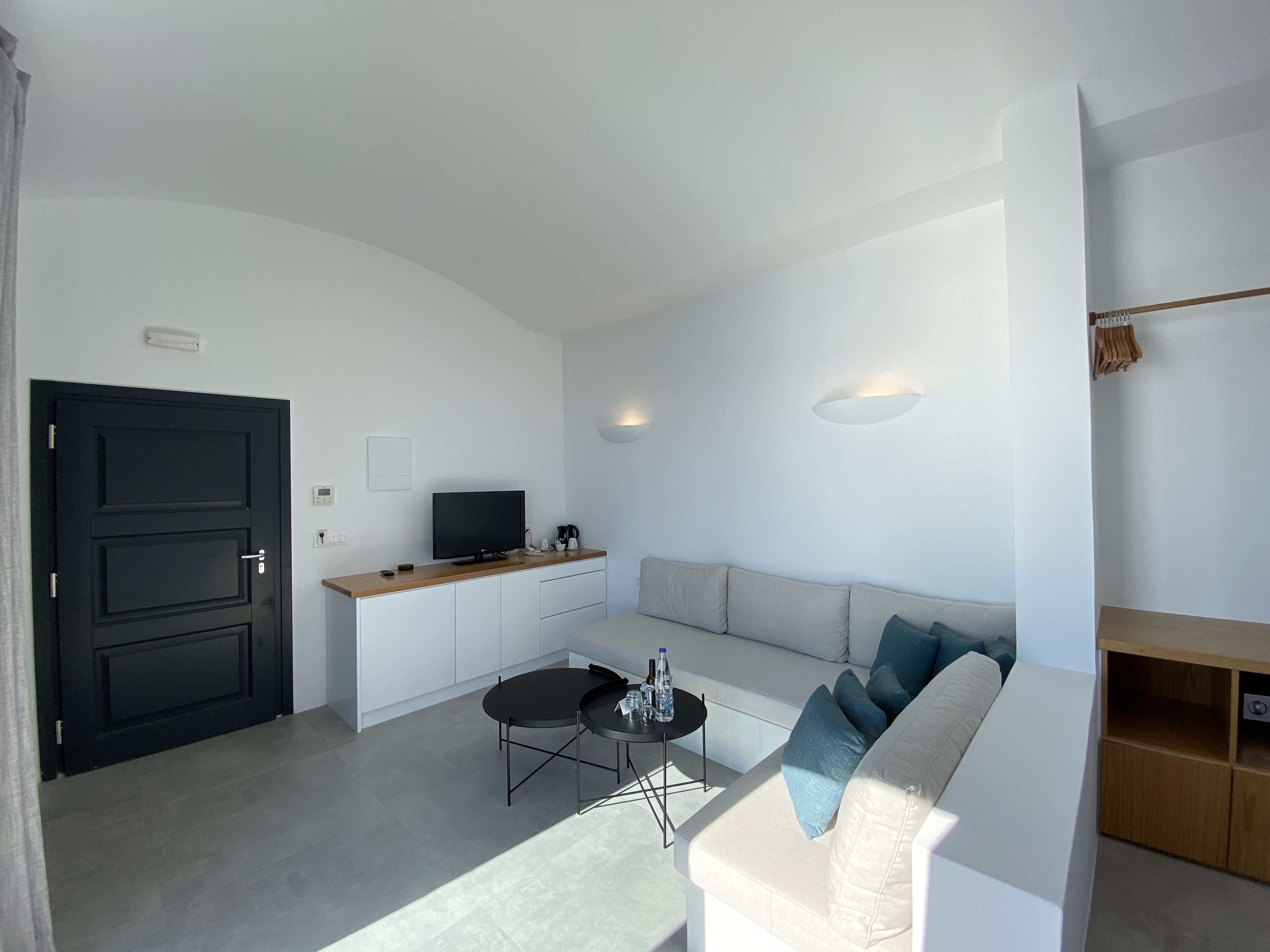 Una sala de estar moderna con un sofá blanco, una mesa de centro negra y un televisor sobre un mueble de madera.