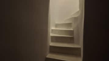 Un escalier doté d’un design architectural unique, avec un mur incurvé et une source de lumière située en haut.
