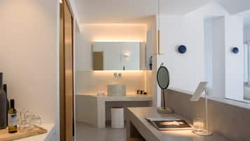 A modern bathroom with a large mirror, a round sink, and a wooden vanity.