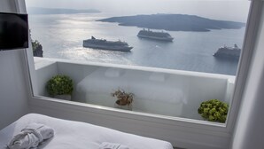 Habitación de hotel con balcón y vista a un cuerpo de agua con barcos.