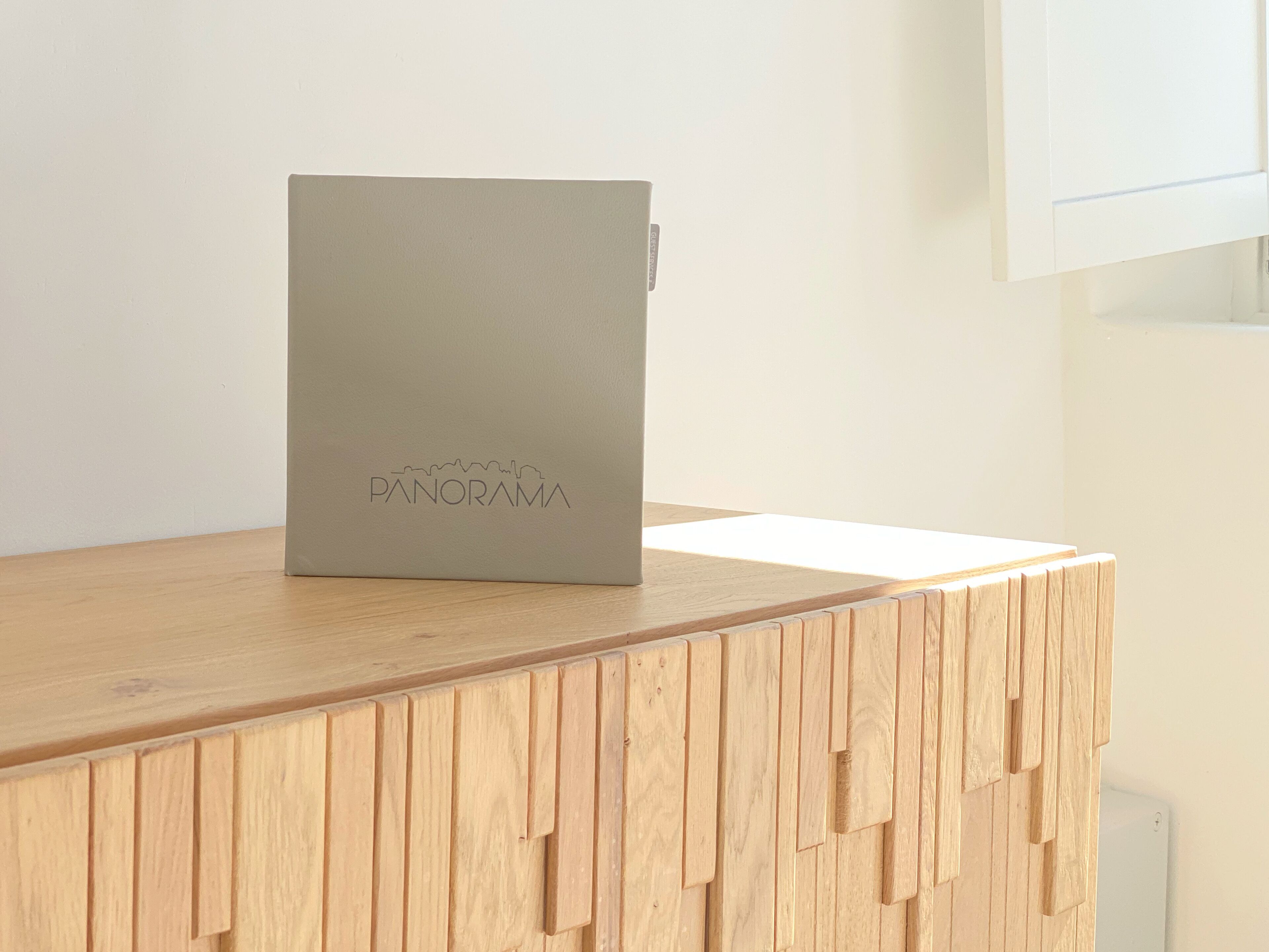 A wooden desk with a grey box labeled "PANORAMA" on top.