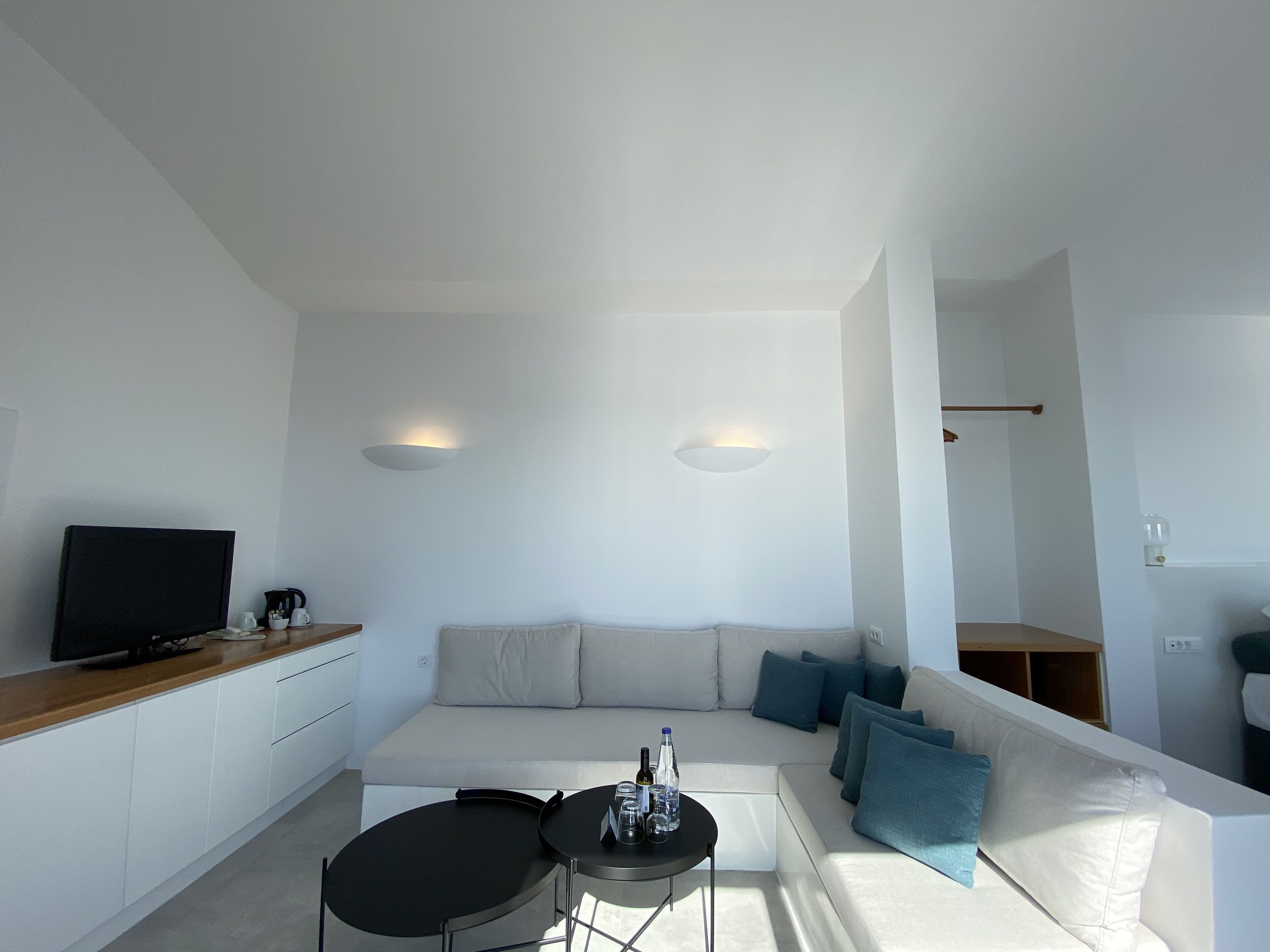 A modern living room with a white sofa, a small black table, and a television on a wooden cabinet.