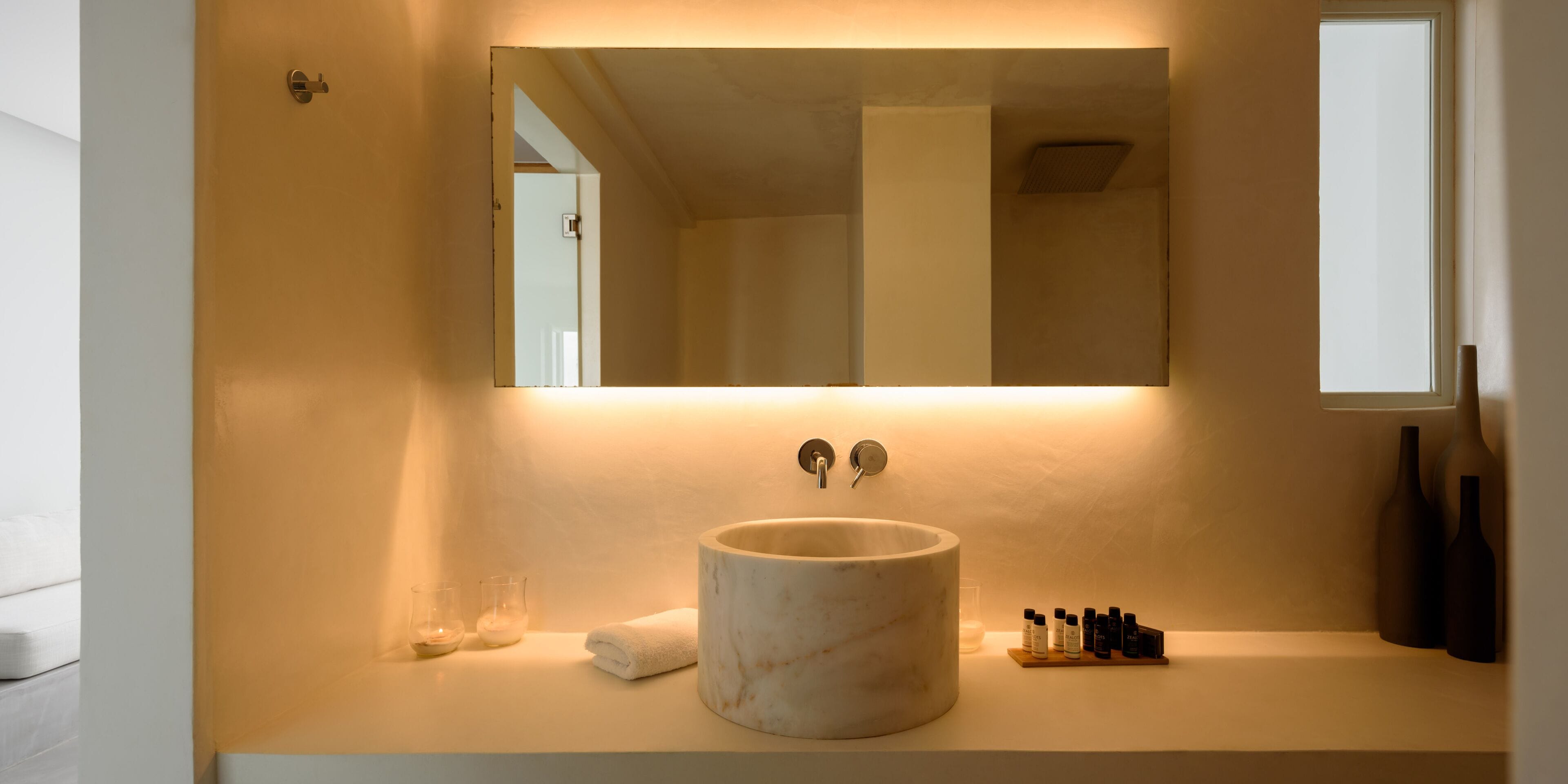 A bathroom with a marble sink, a mirror, and a shelf with toiletries.