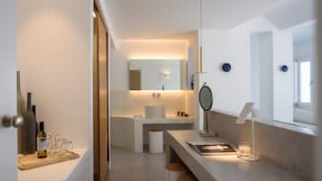 A modern bathroom with a vanity, mirror, and a bottle of wine on the counter.