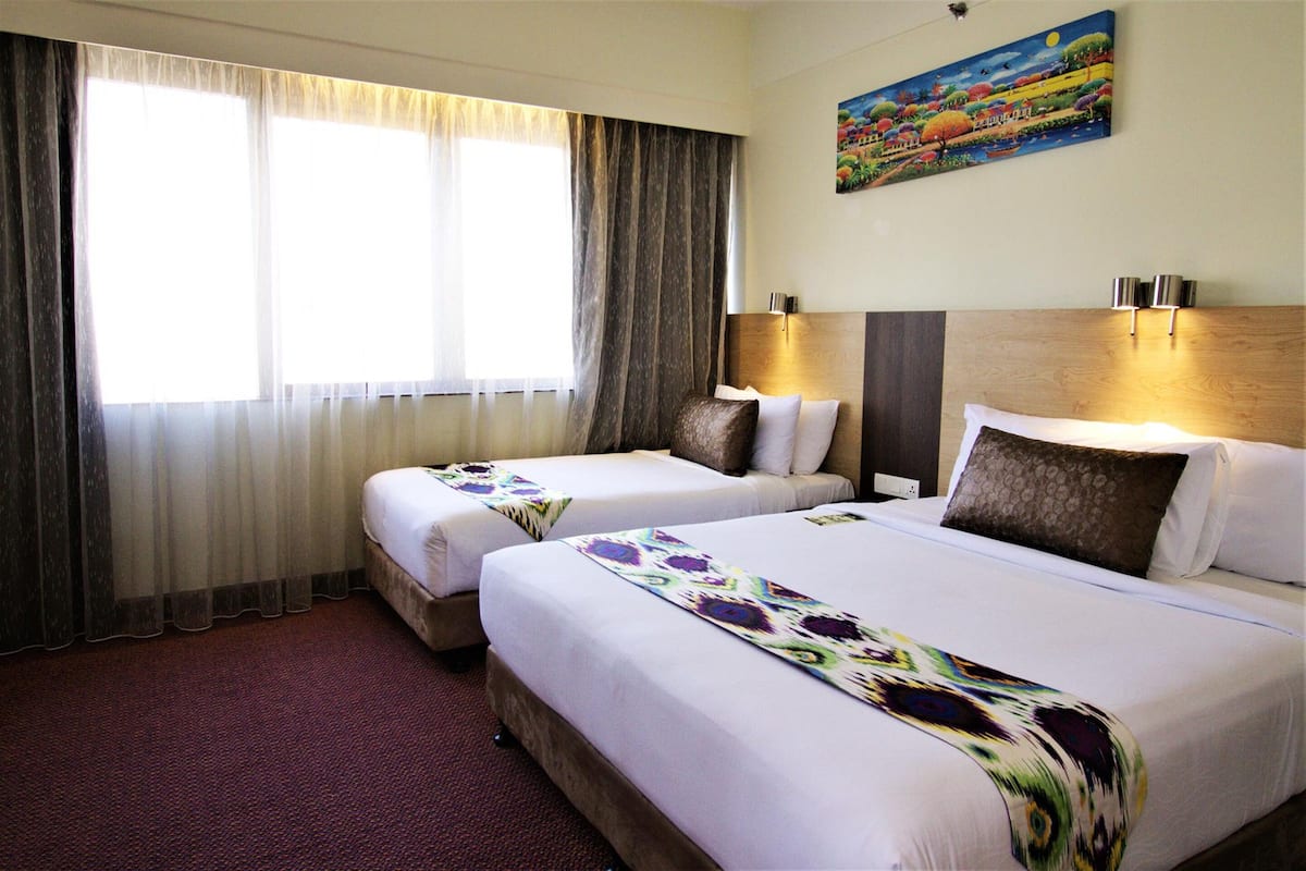 A hotel room with two beds, a large window with curtains, a painting on the wall, and a carpeted floor.