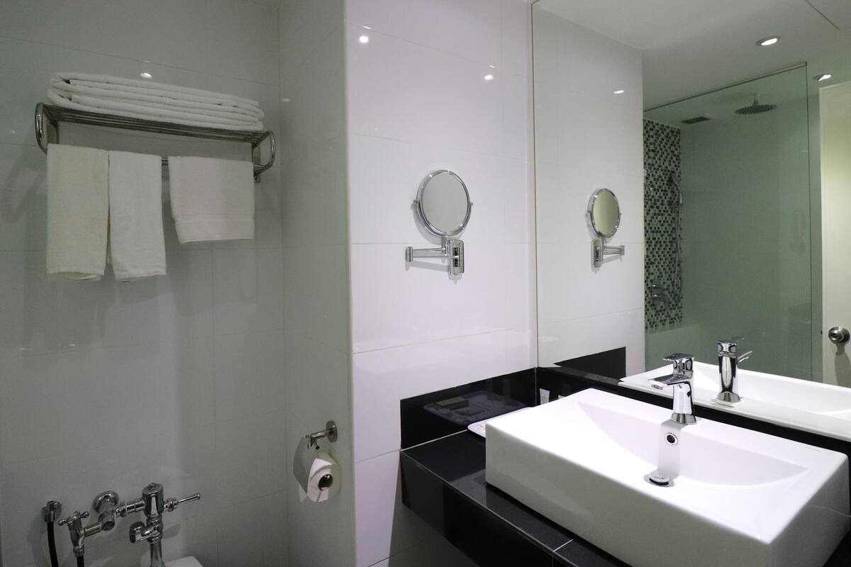 A modern bathroom with two sinks, a large mirror, and a towel rack.