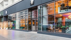 A modern building with large glass windows, a visible entrance, and outdoor seating area. - Appart'City Collection Paris Grande Bibliothèque (Paris)