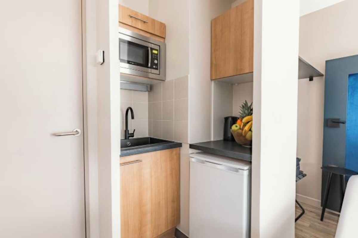 A compact kitchen with a microwave, sink, and wooden cabinets.
