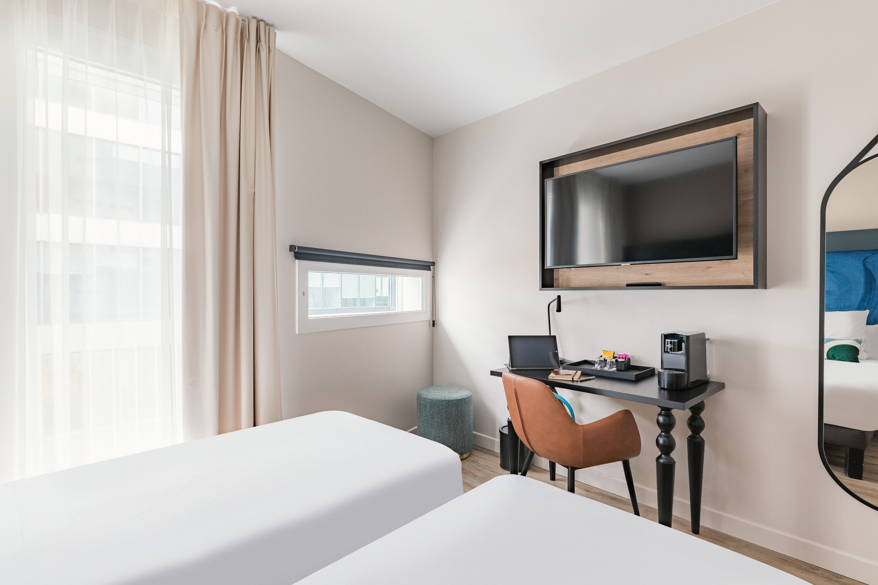 Une chambre d’hôtel avec deux lits, un bureau avec un ordinateur, une machine à café et une télévision.