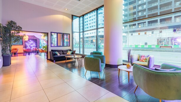 A modern hotel lobby with a reception area, seating arrangements, and large windows offering views of the city. - Appart'City Collection Paris Grande Bibliothèque (Paris)