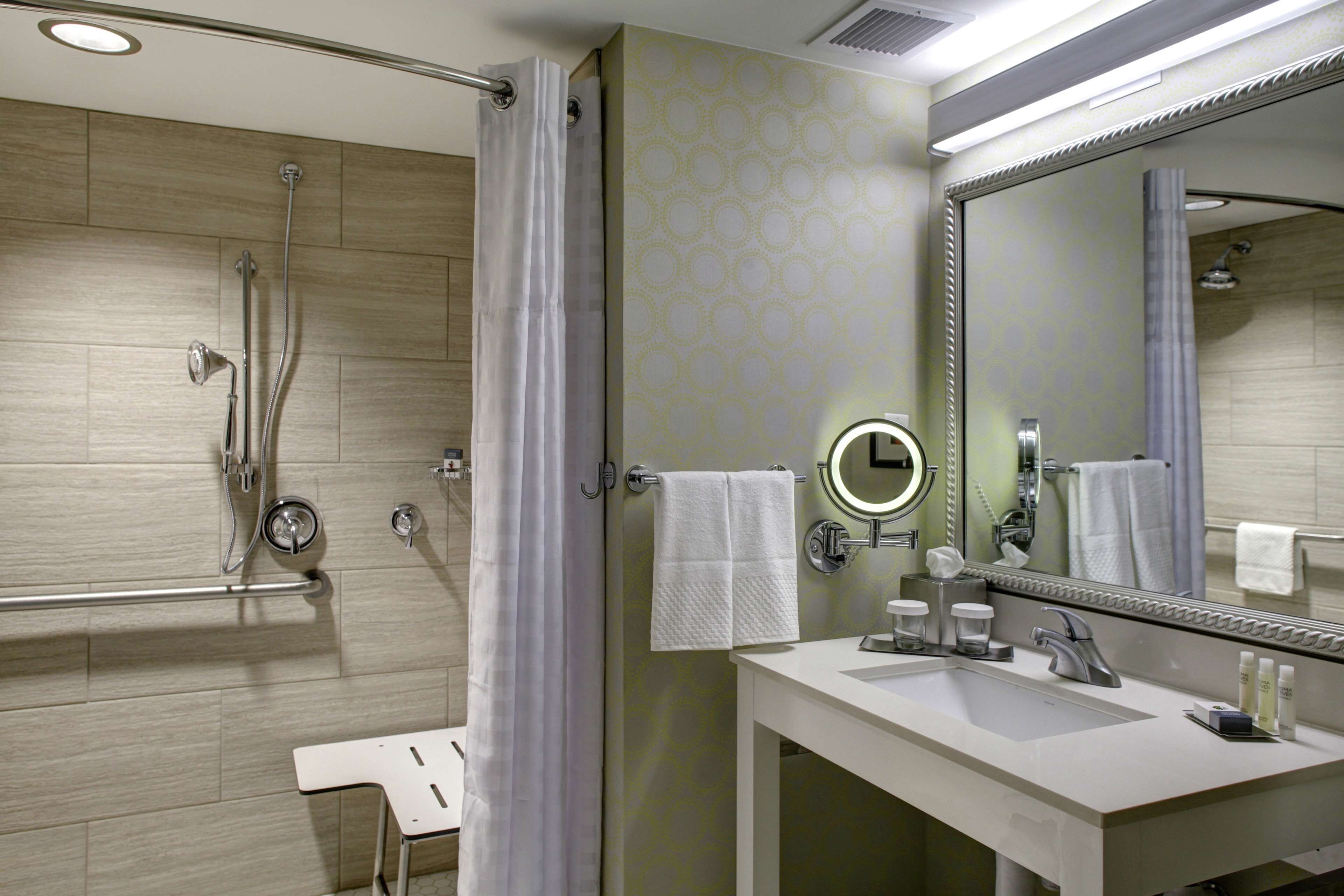 A modern bathroom with a shower, a sink, and a large mirror.