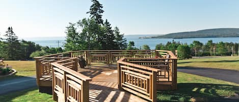 A wooden deck with a view of the sea and hills.