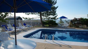 Una piscina al aire libre de temporada, sombrillas