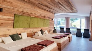 Una habitación de hotel moderna con paneles de madera, un ventanal grande y una zona de estar con sillas y una mesa.