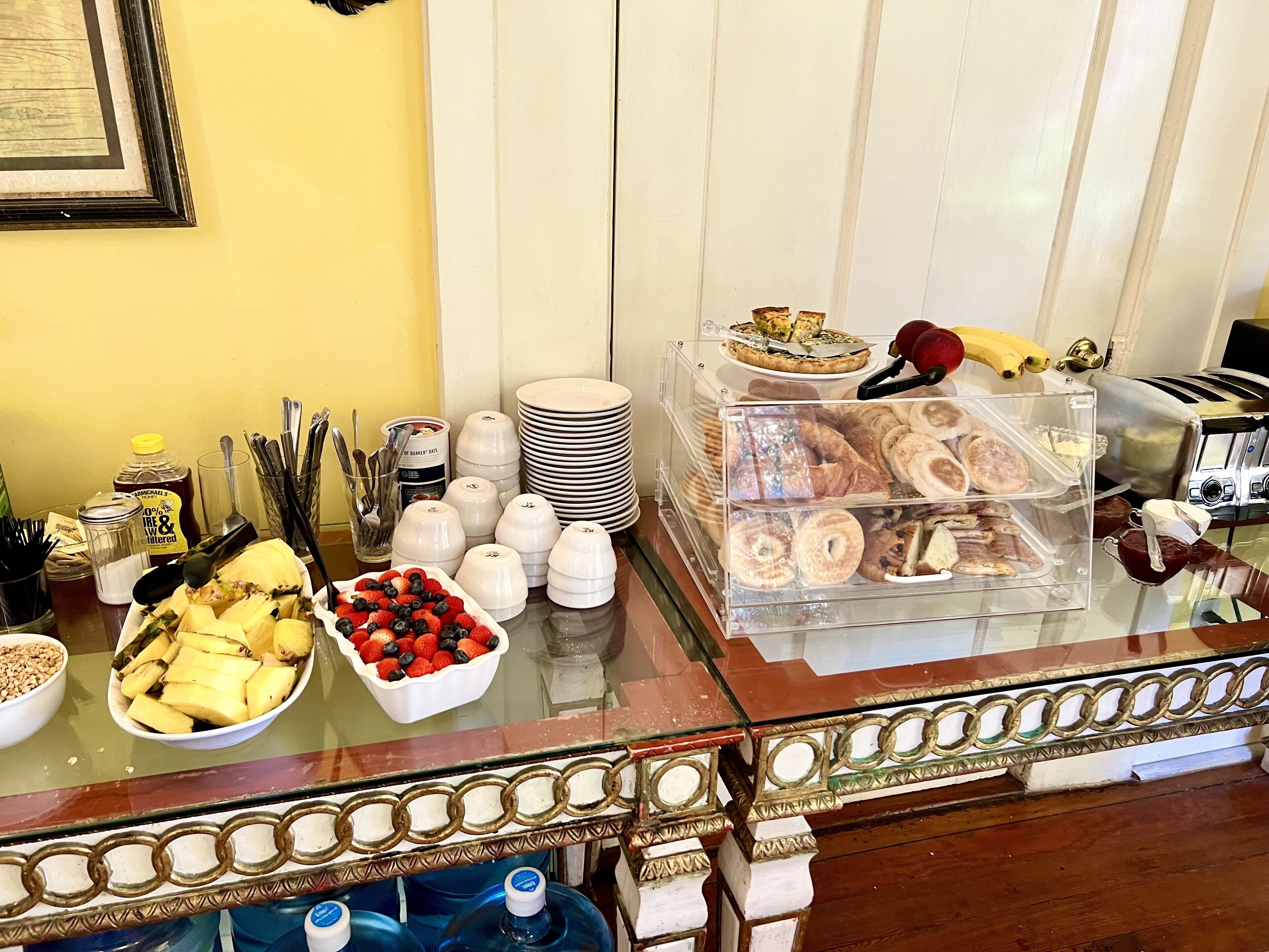 A buffet table with various food items, including fruits, pastries, and condiments.