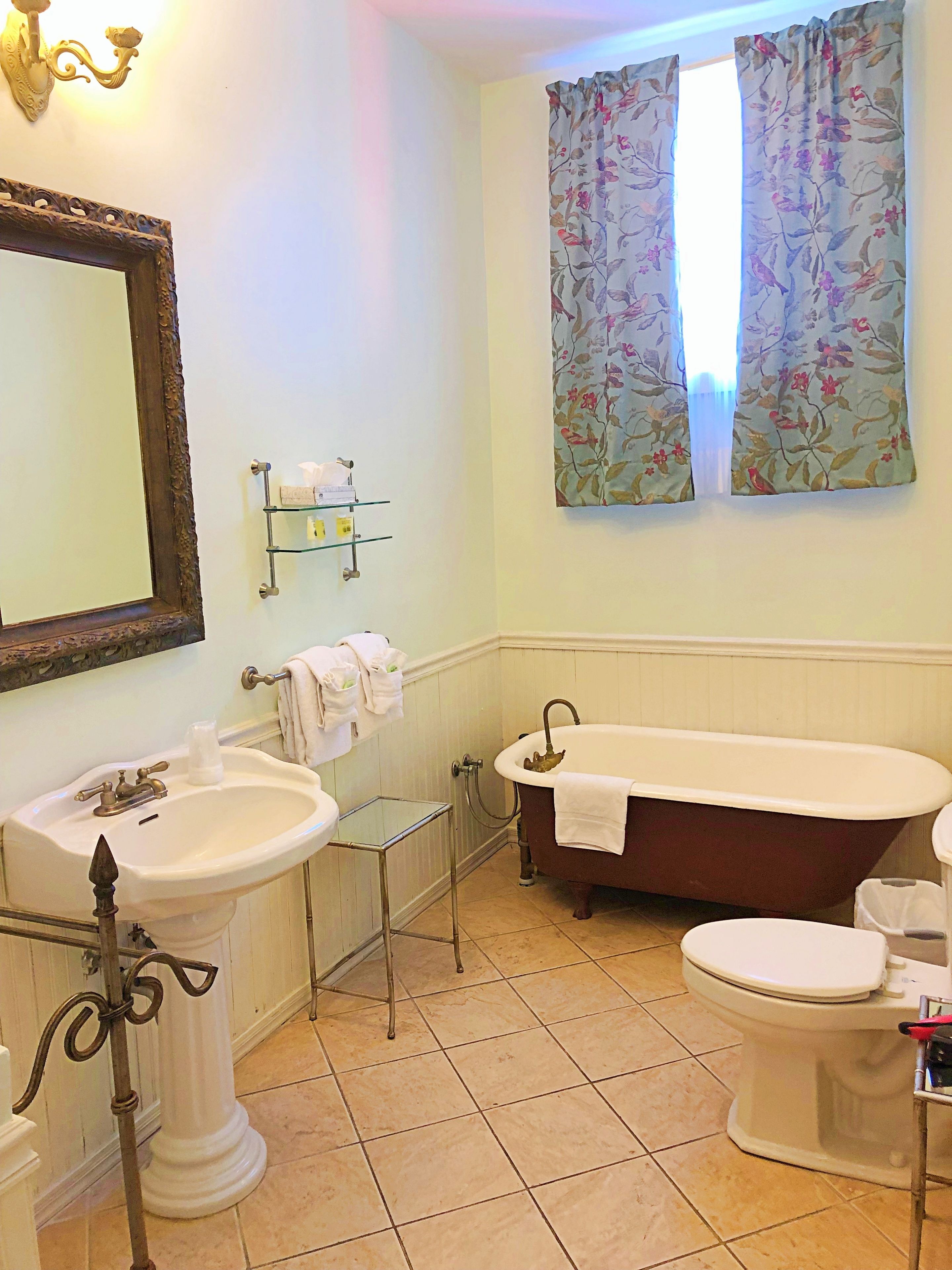 A bathroom with a pedestal sink, a clawfoot bathtub, and a toilet.