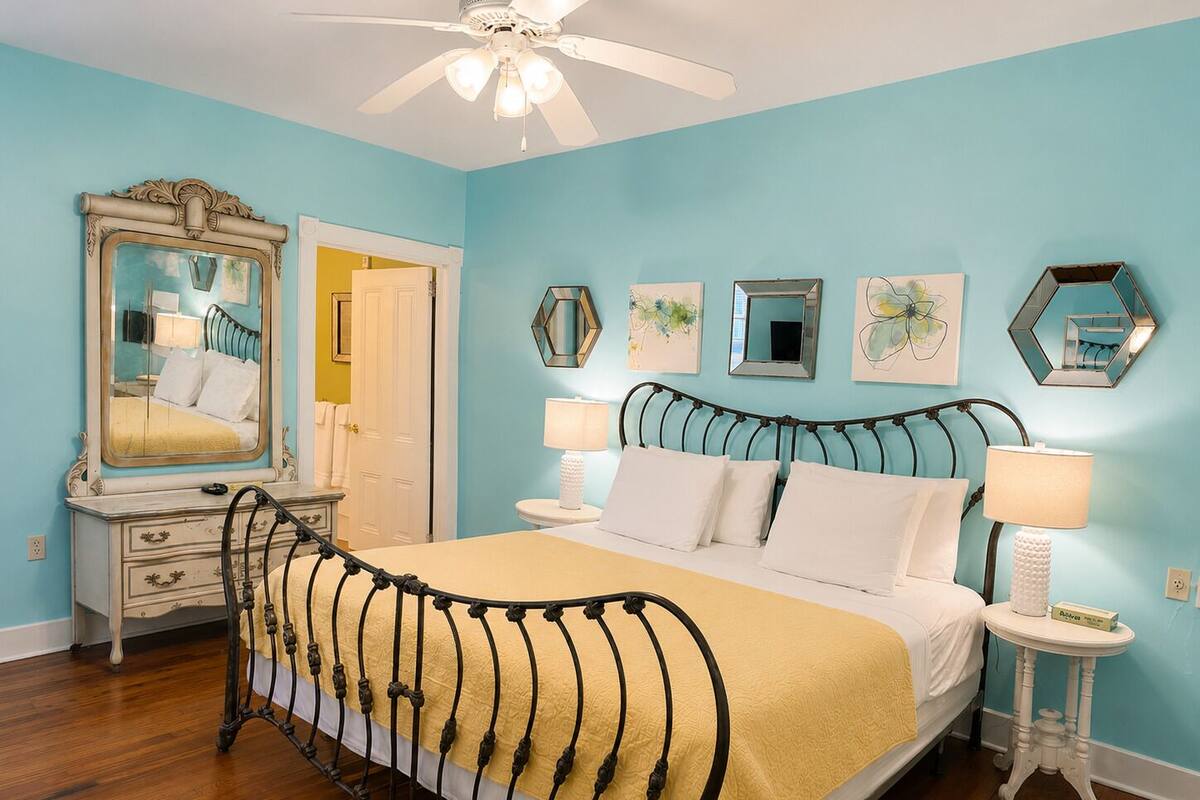 A bedroom with a bed, a nightstand, a dresser, a mirror, and a ceiling fan.
