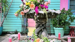 A multi-tiered stone fountain with cascading water, surrounded by a variety of colorful flowers. - Creole Gardens Guesthouse and Inn (New Orleans)