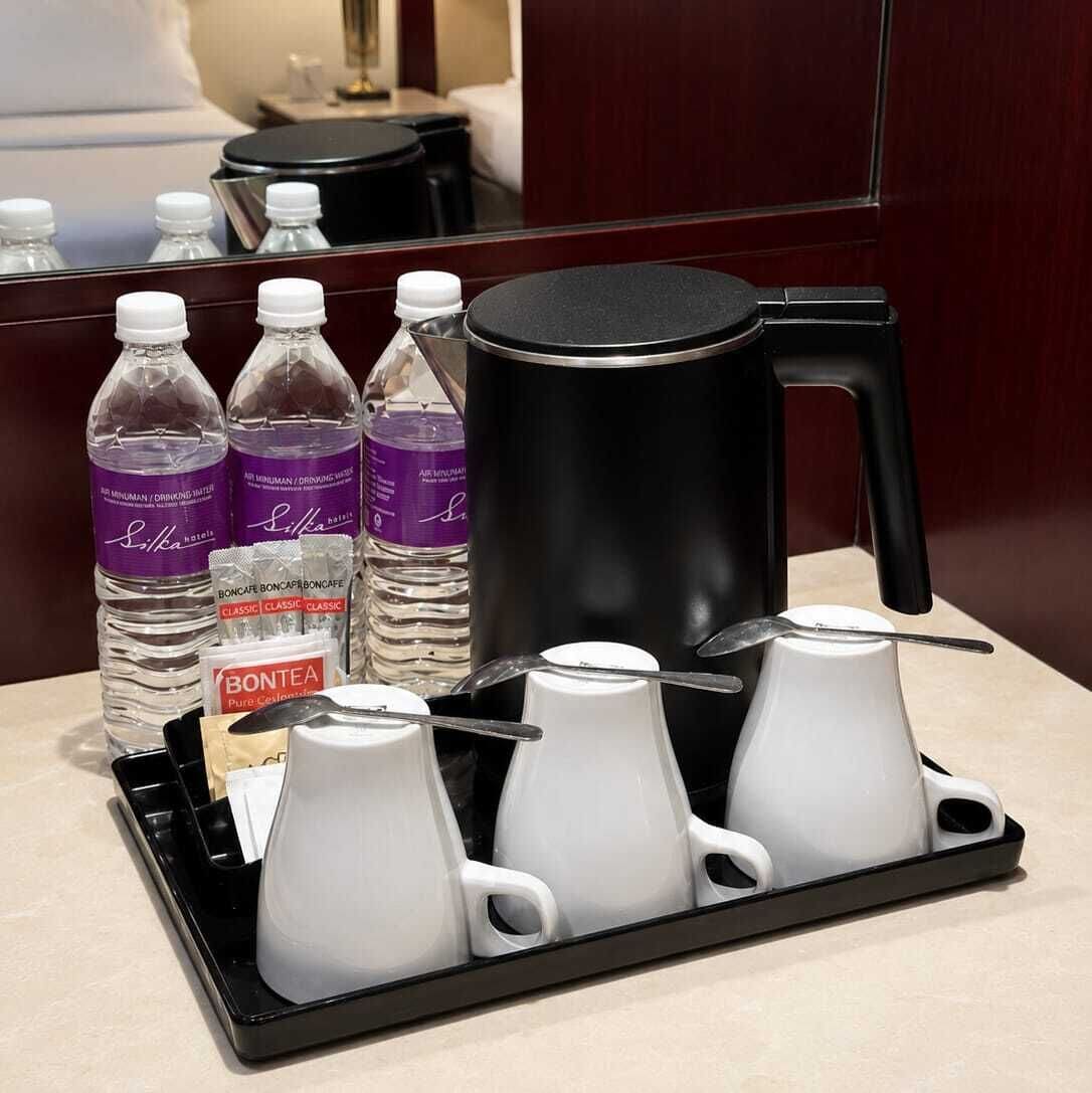 A hotel room's minibar setup with bottled water, a coffee maker, and tea pots.