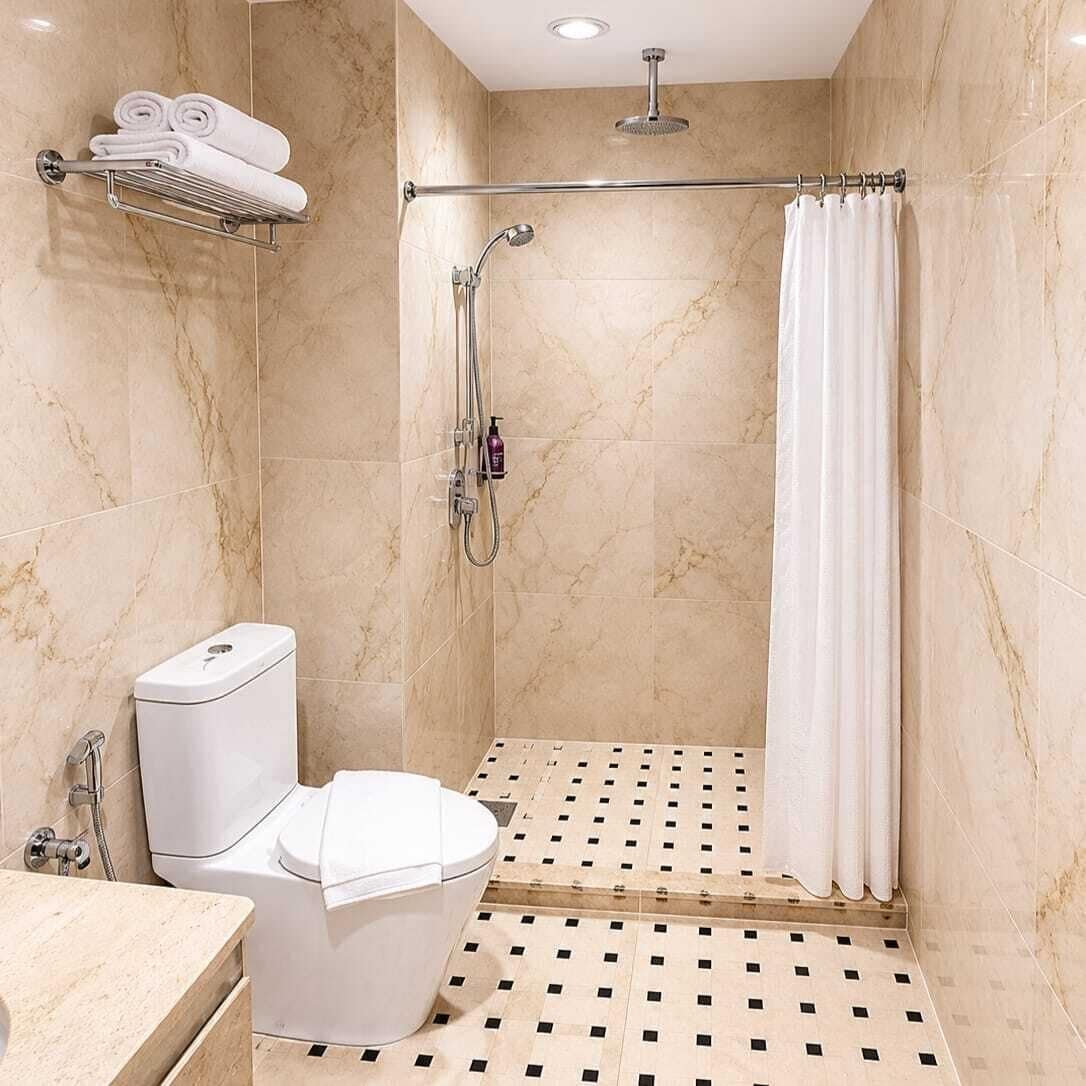 A bathroom with a shower, toilet, and a towel rack.