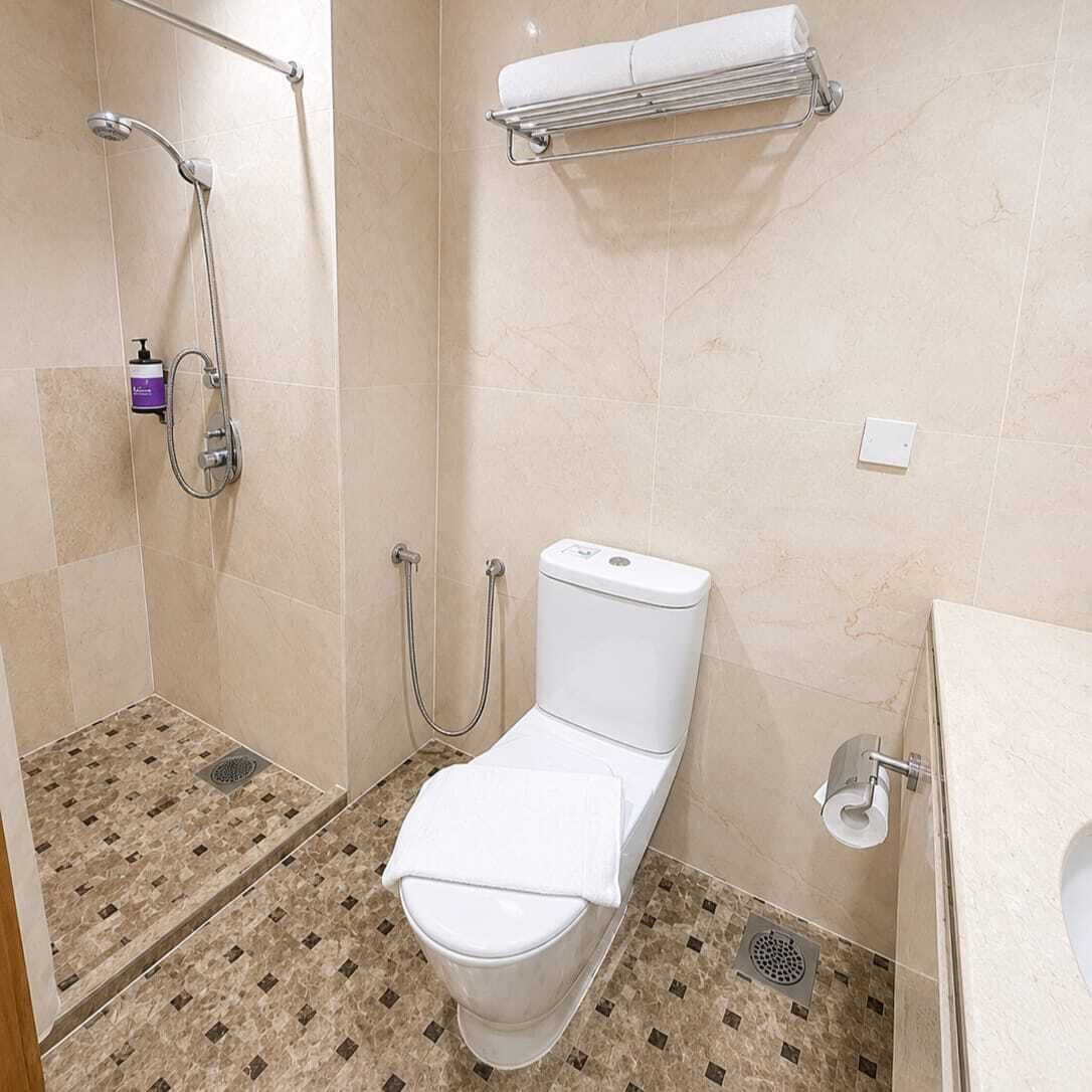 A bathroom with a shower, toilet, and a towel rack.