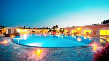 Alberca techada, alberca al aire libre y sombrillas en la alberca