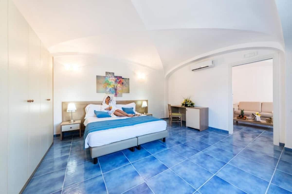A bedroom with a bed, bedside tables, a desk, and a chair.