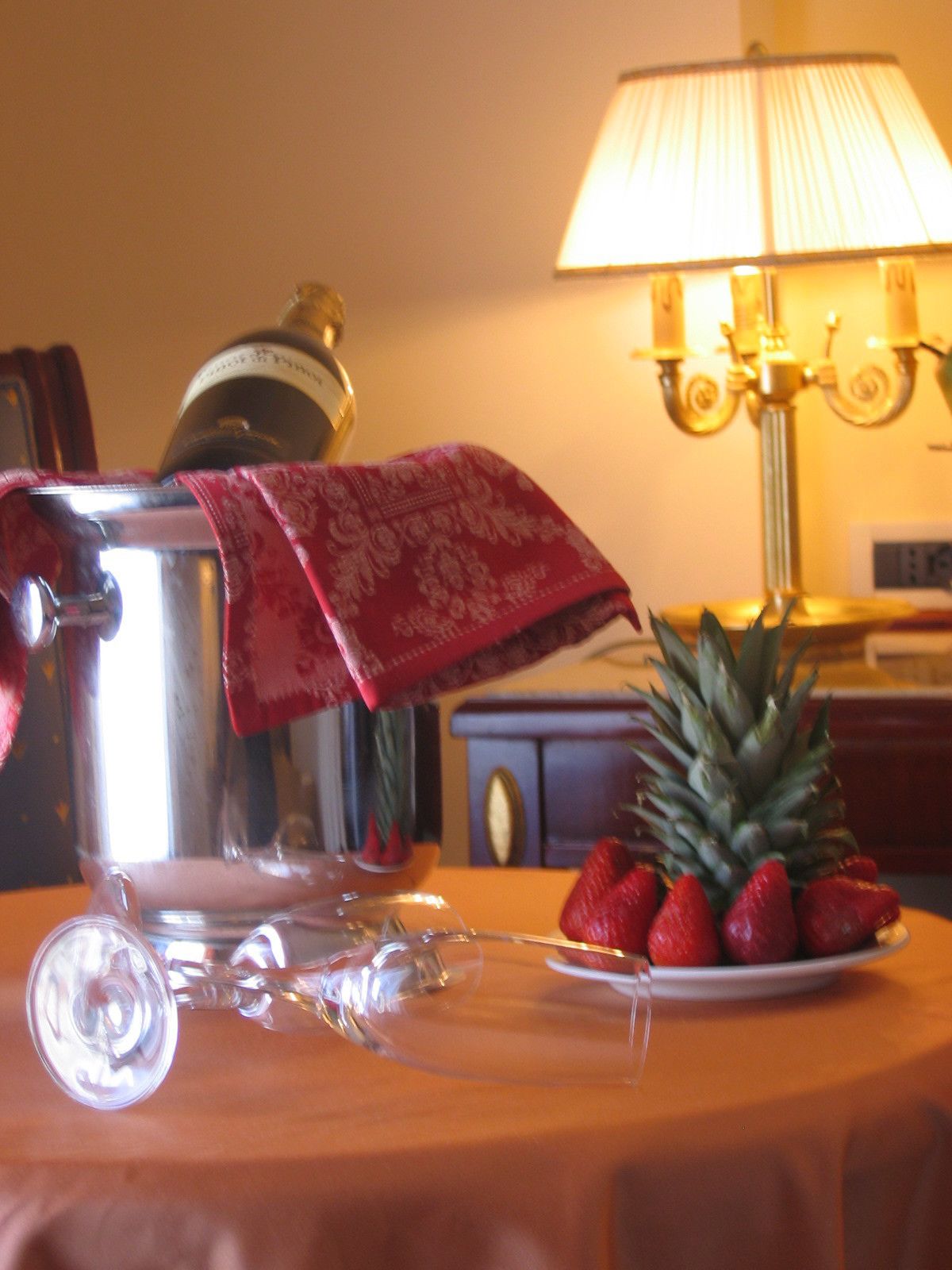 A table with a glass pitcher, a plate of strawberries, and a pineapple.