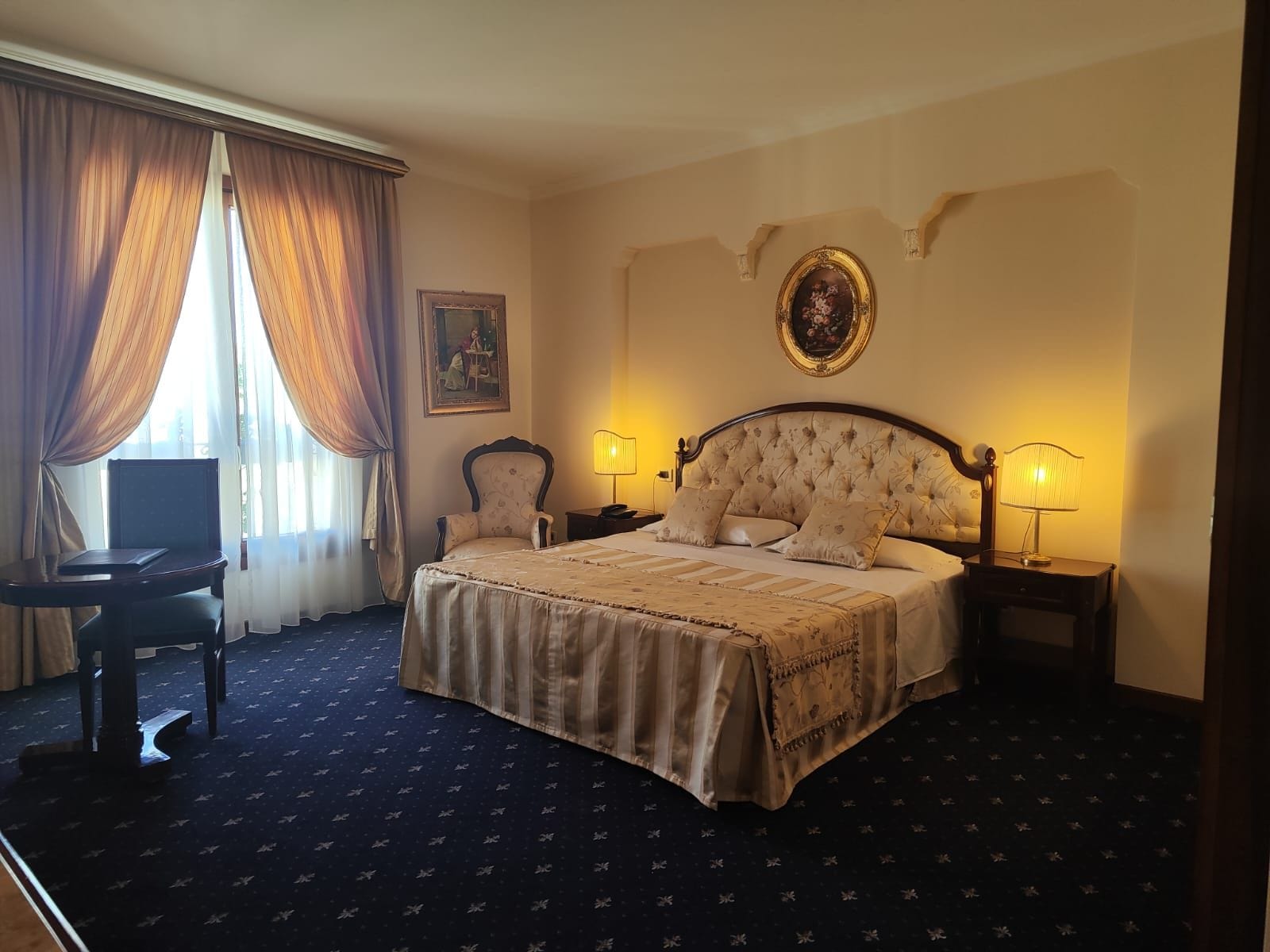 A hotel room with a large bed, two bedside tables, a desk, and a chair.