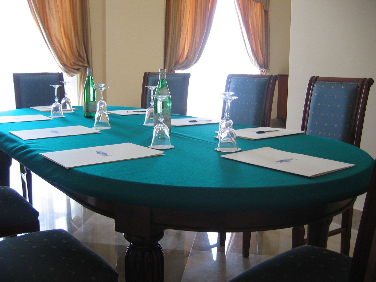 Une salle de conférence avec une table ronde, des chaises et une nappe de couleur turquoise.