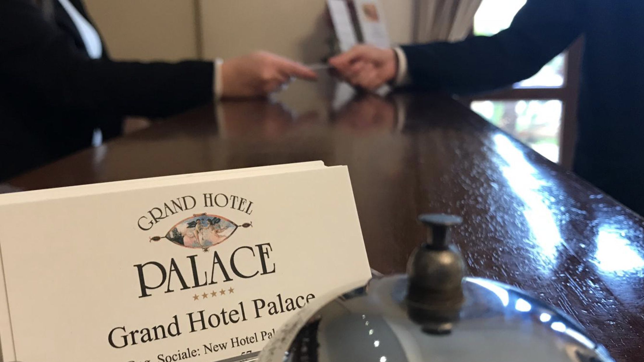 A sign for Grand Hotel Palace with a bell and a key.