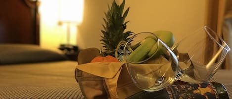 A bottle of Floramum wine, a pineapple, a green banana, and a glass on a patterned tablecloth.